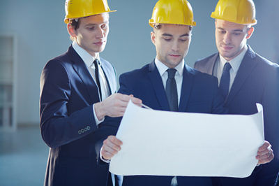 Three executive in construction with schematics