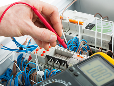 electrician testing switchboard equipment with a multi-meter with effective diligence