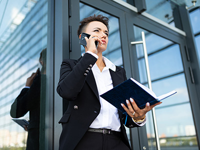 Building management | Building Supervisor outside commercial building on the phone with note book