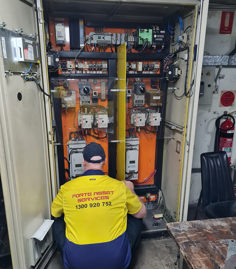Forte Asset Services Field Technician working on a control panel serving the travelator in Sydney, NSW