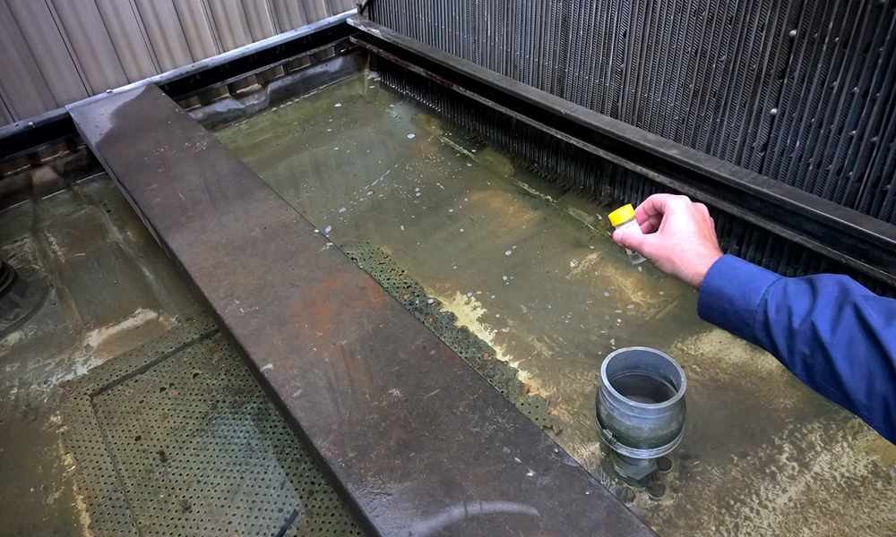 inside the HVAC Mecchanical Services Cooling tower taking a sample of the condenser water for testng by a third party